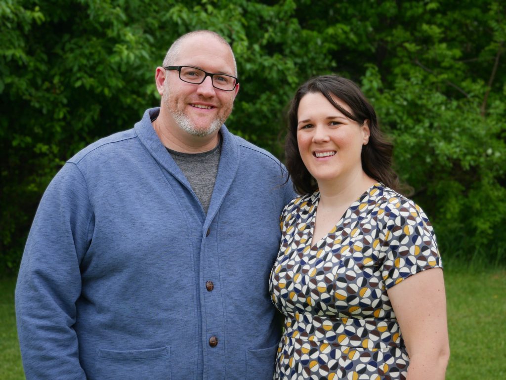 heather (grovemiller) curtis and husband pose in front of trees