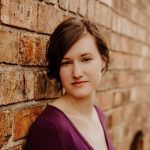 Ellie Zumbah leaning against brick wall