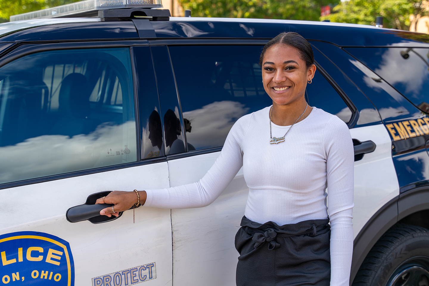 female student with hand on door handle of police emergency vehicle