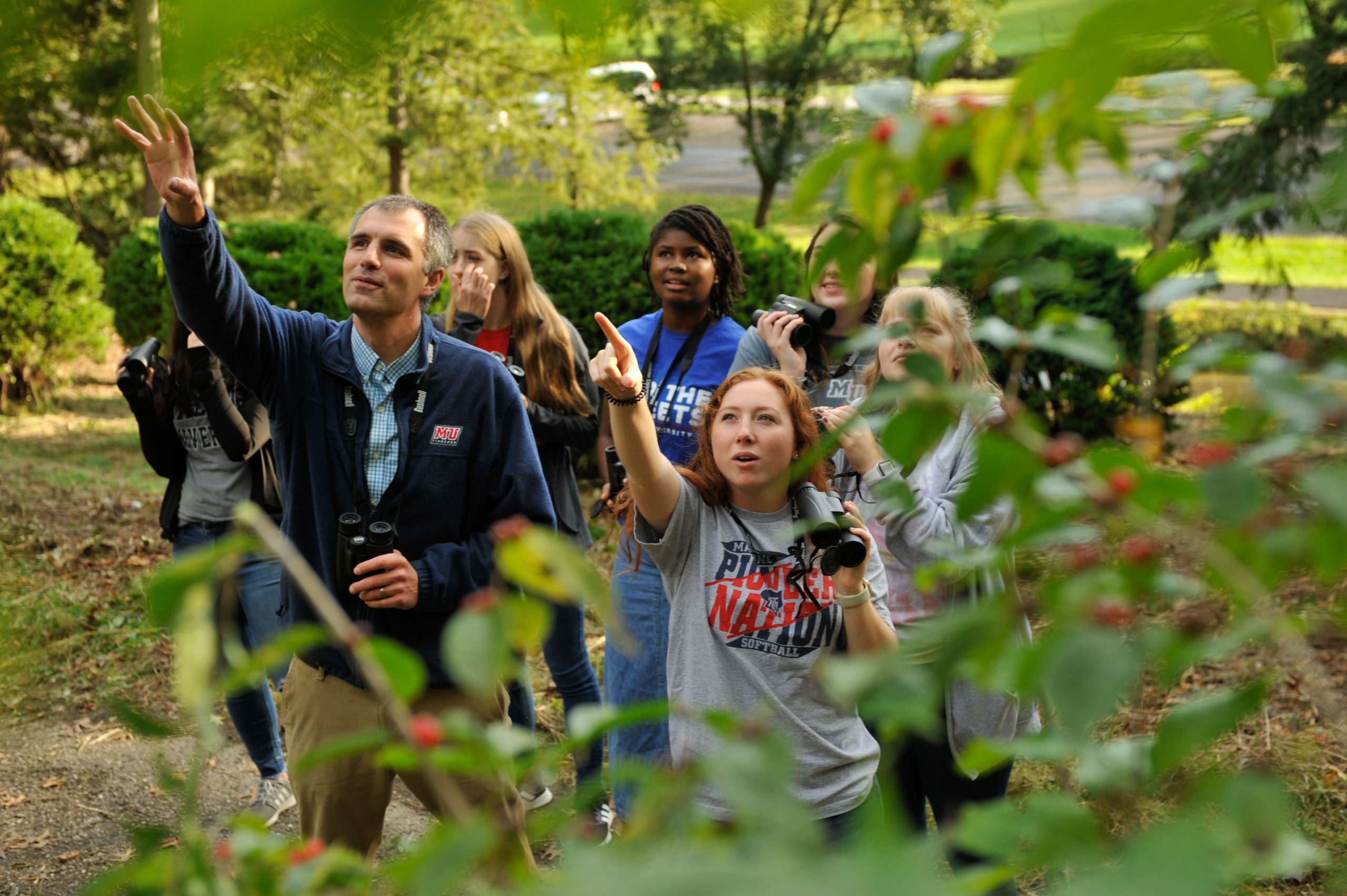 ornithology students and a professor pointing and using binoculars
