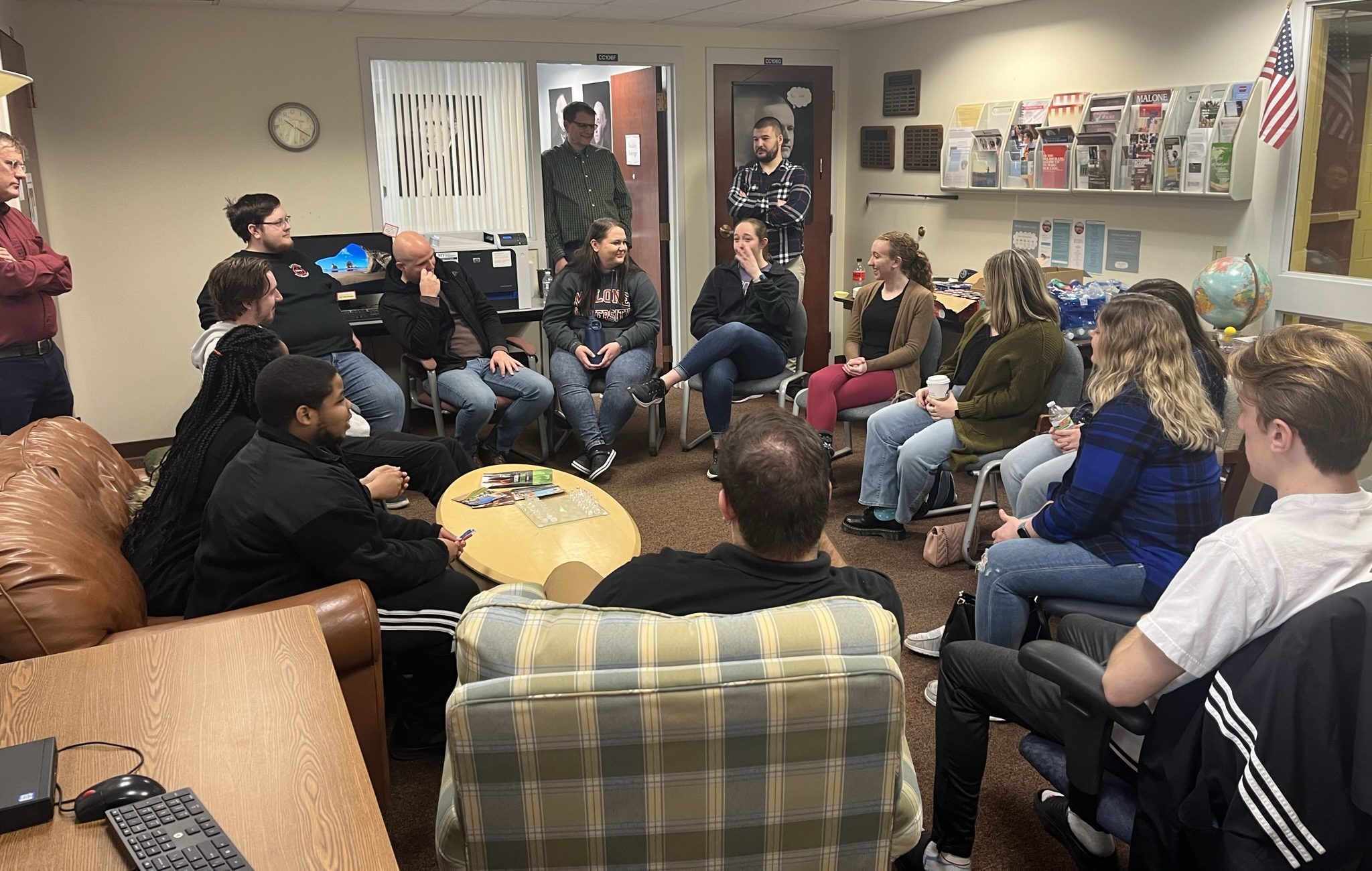 seated History Majors and Alumni pictured in room with Scott Waalkes and Jay Case standing, looking on