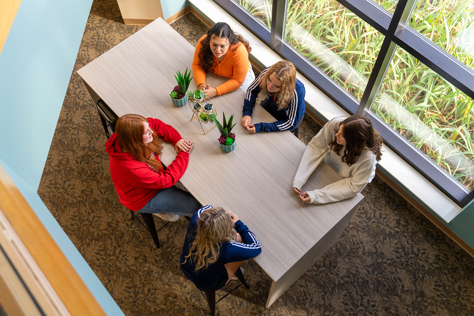Group of five students sitting around a table shown from above