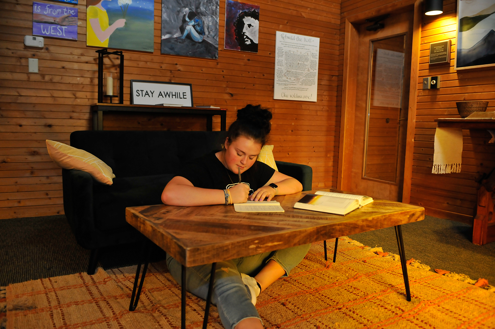 female student seated on floor, writing at low table