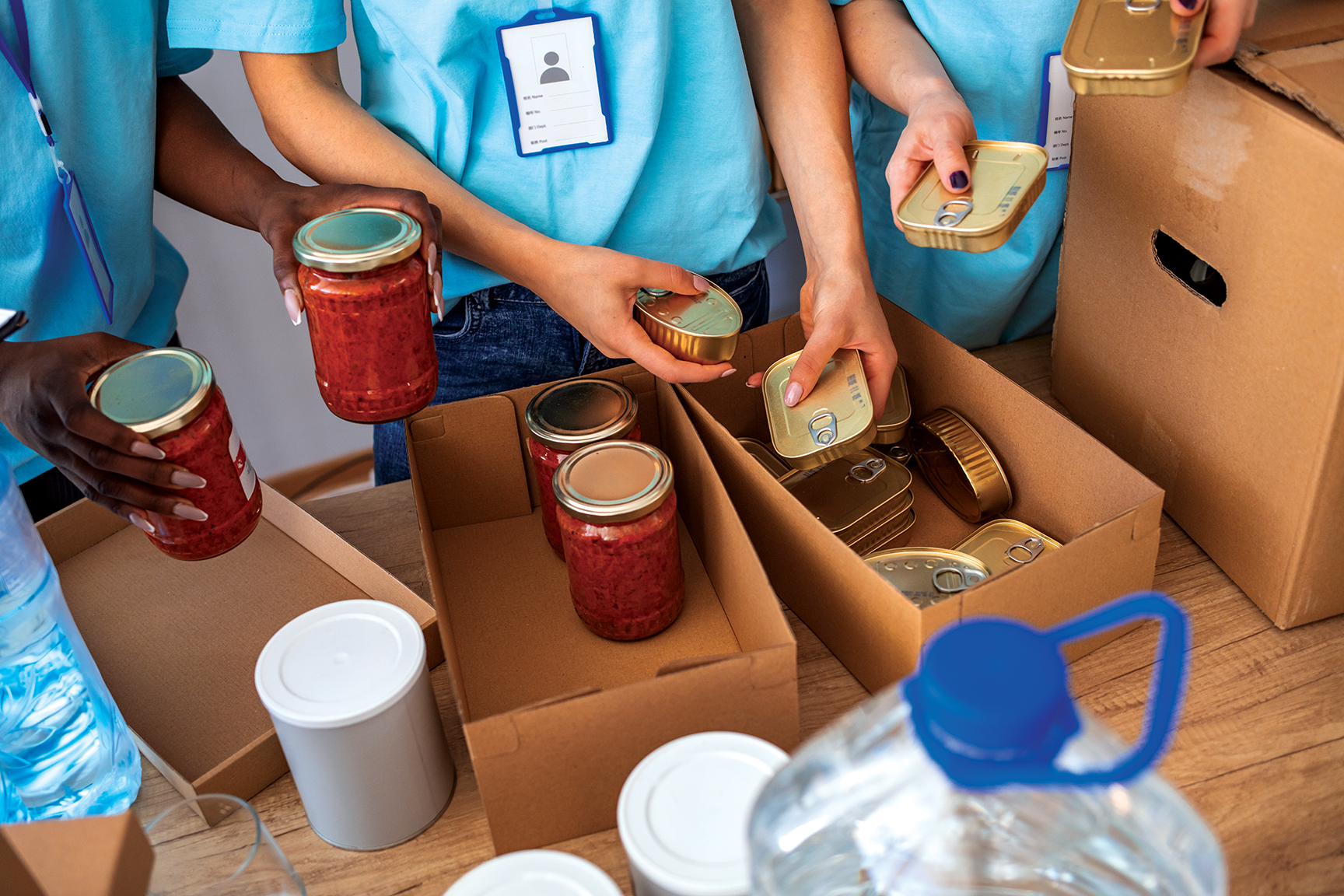 hands of people filling cardboard boxes with food donations