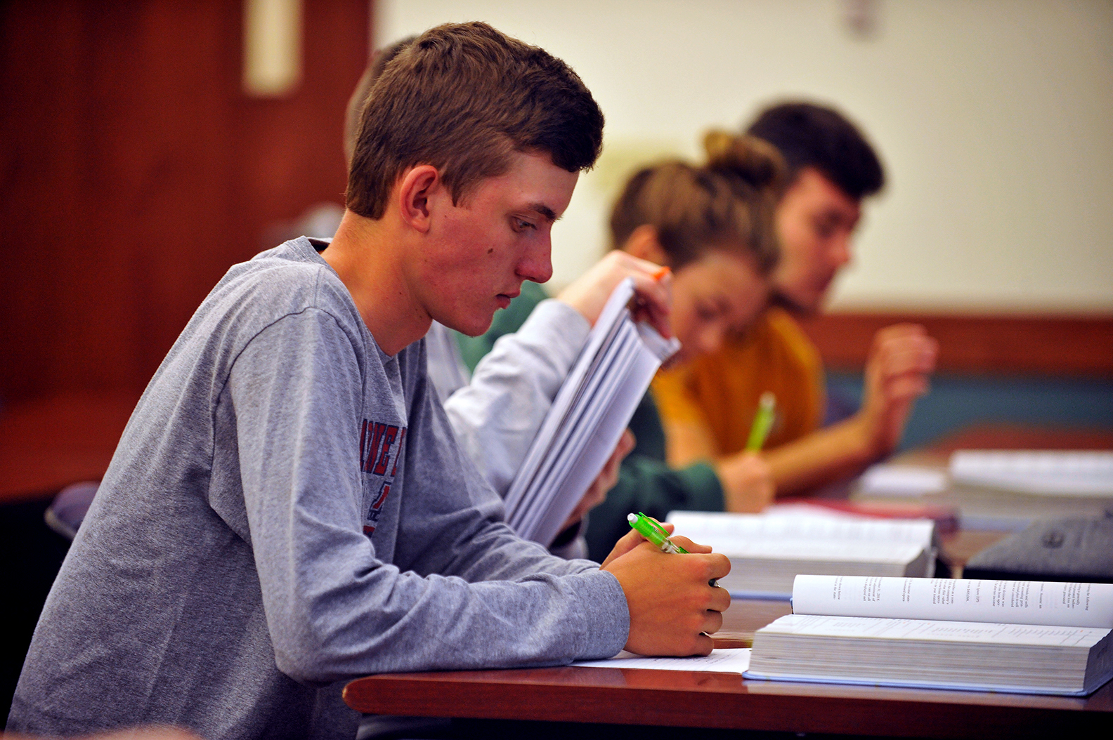 4 students seated at table with open textbooks