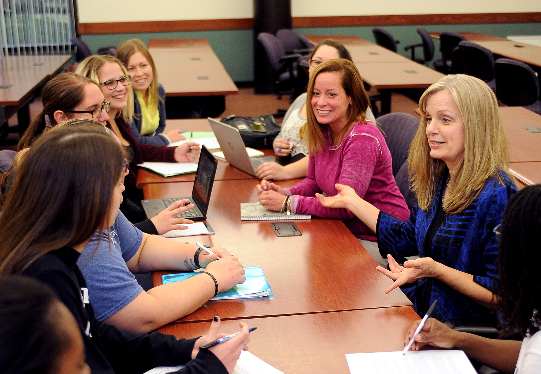 Kara Kaelber seated at table in Mitchell Hall with students gathered around her