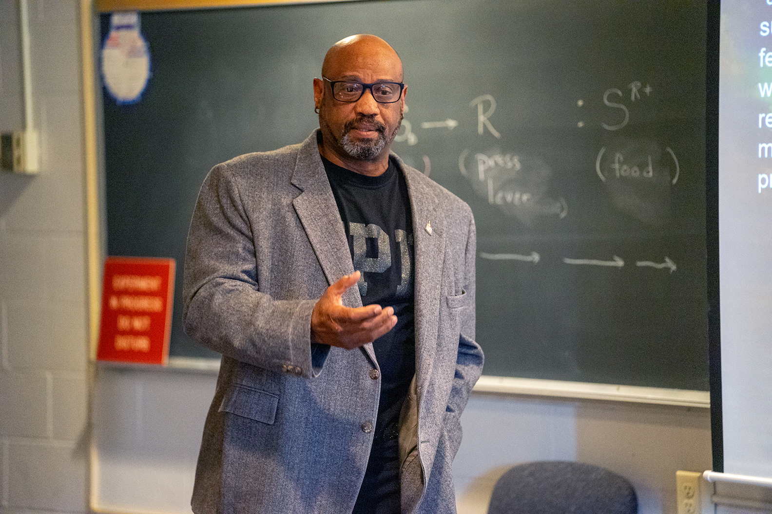 male teacher gesturing in front of chalkboard