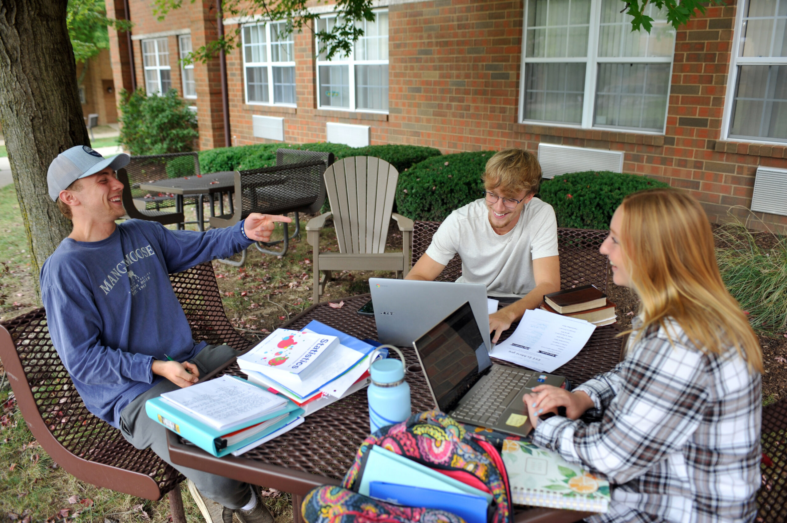 Three Malone students sit together outdoors studying