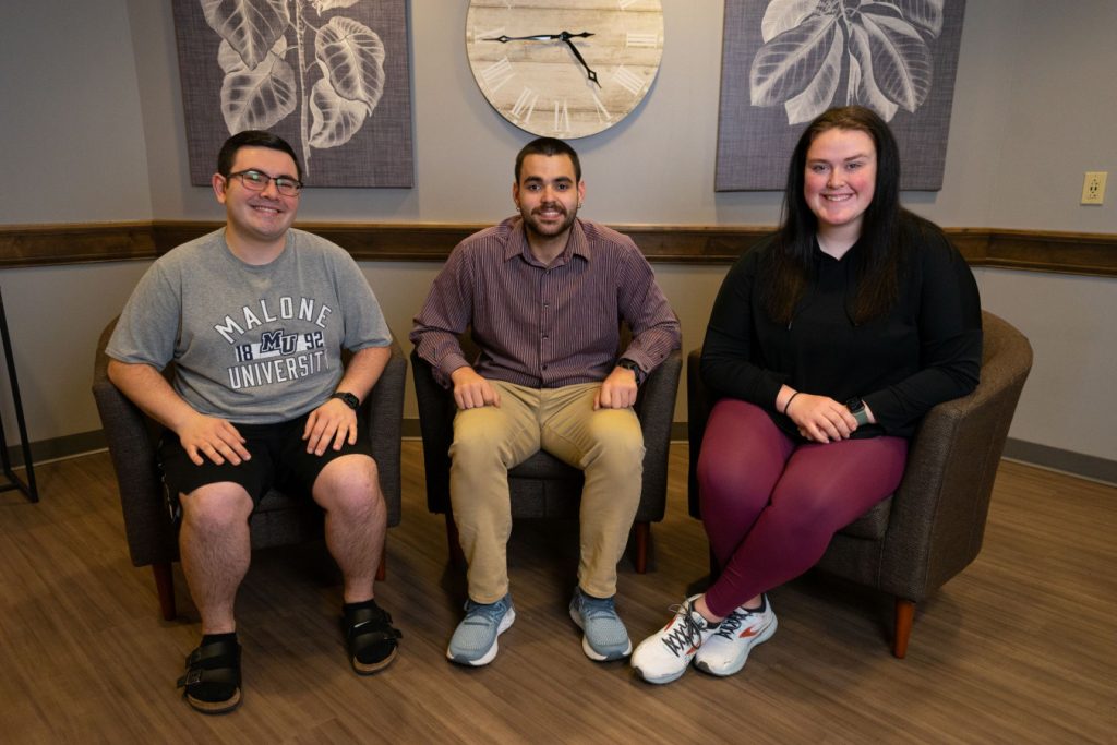 Three students sitting in lounge chairs smiling