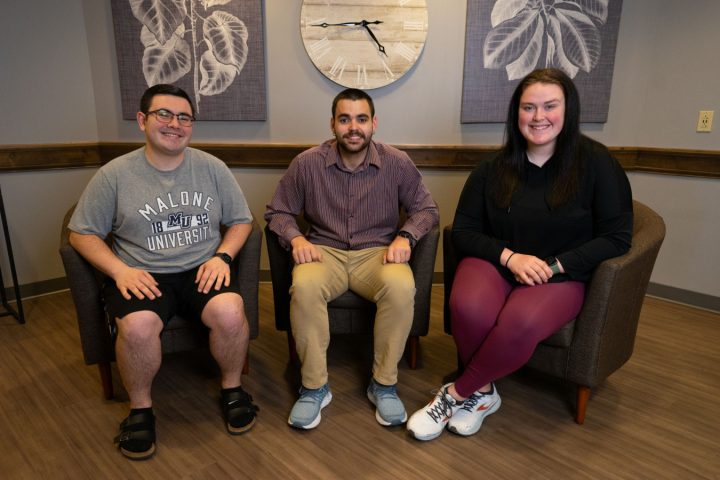 Three students sitting in lounge chairs smiling