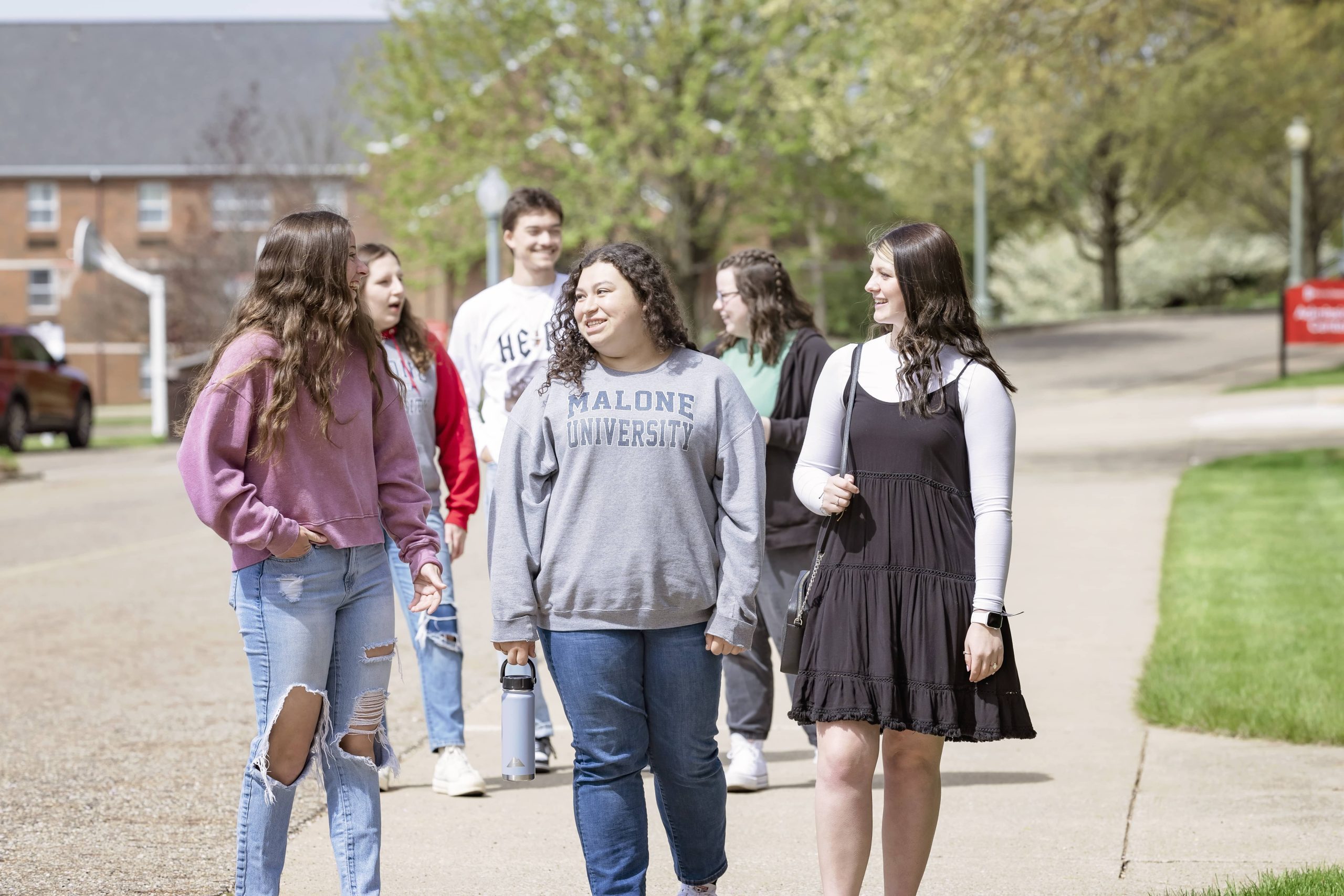 Group of three girls walk outdoors on campus on a sunny day