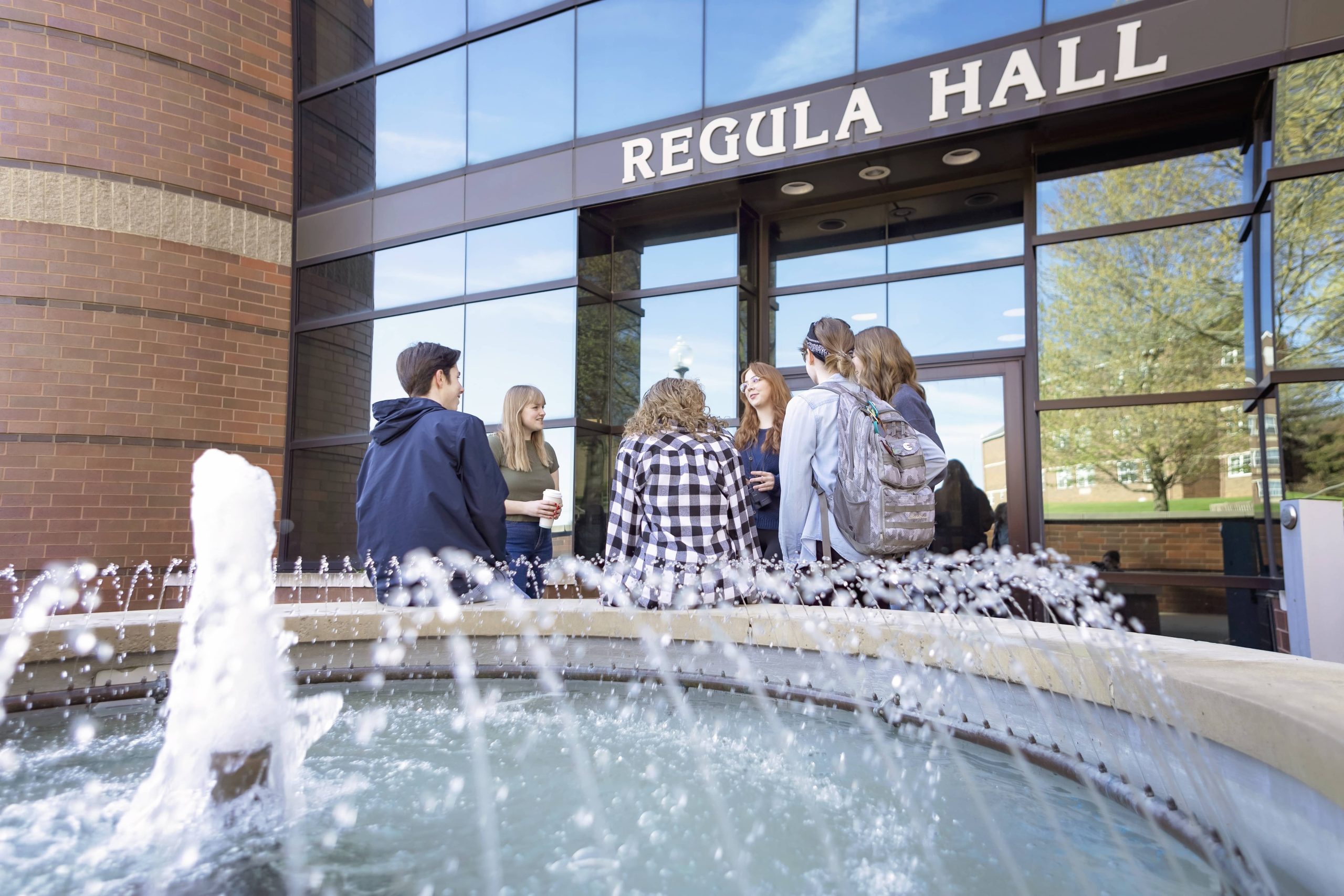 group of students sitting by a foundation on Malone's campus