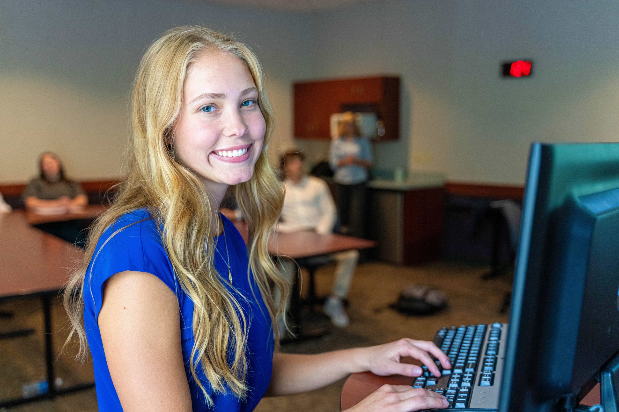 blond female student and computer smiling toward camera