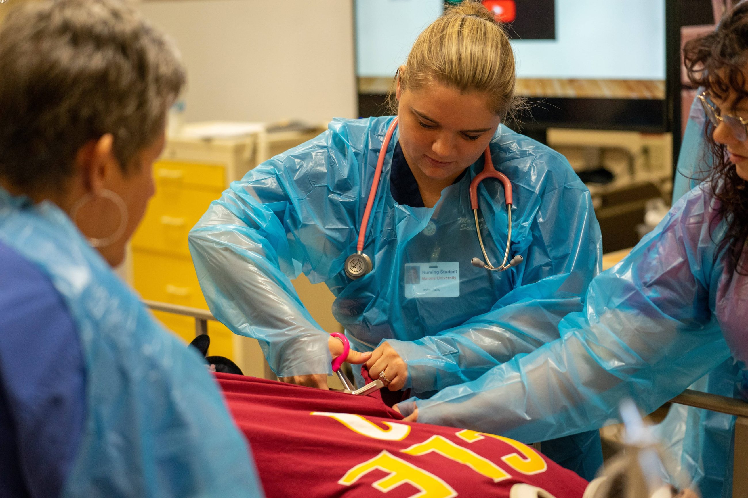 female nursing student using scissors while attending to a patient
