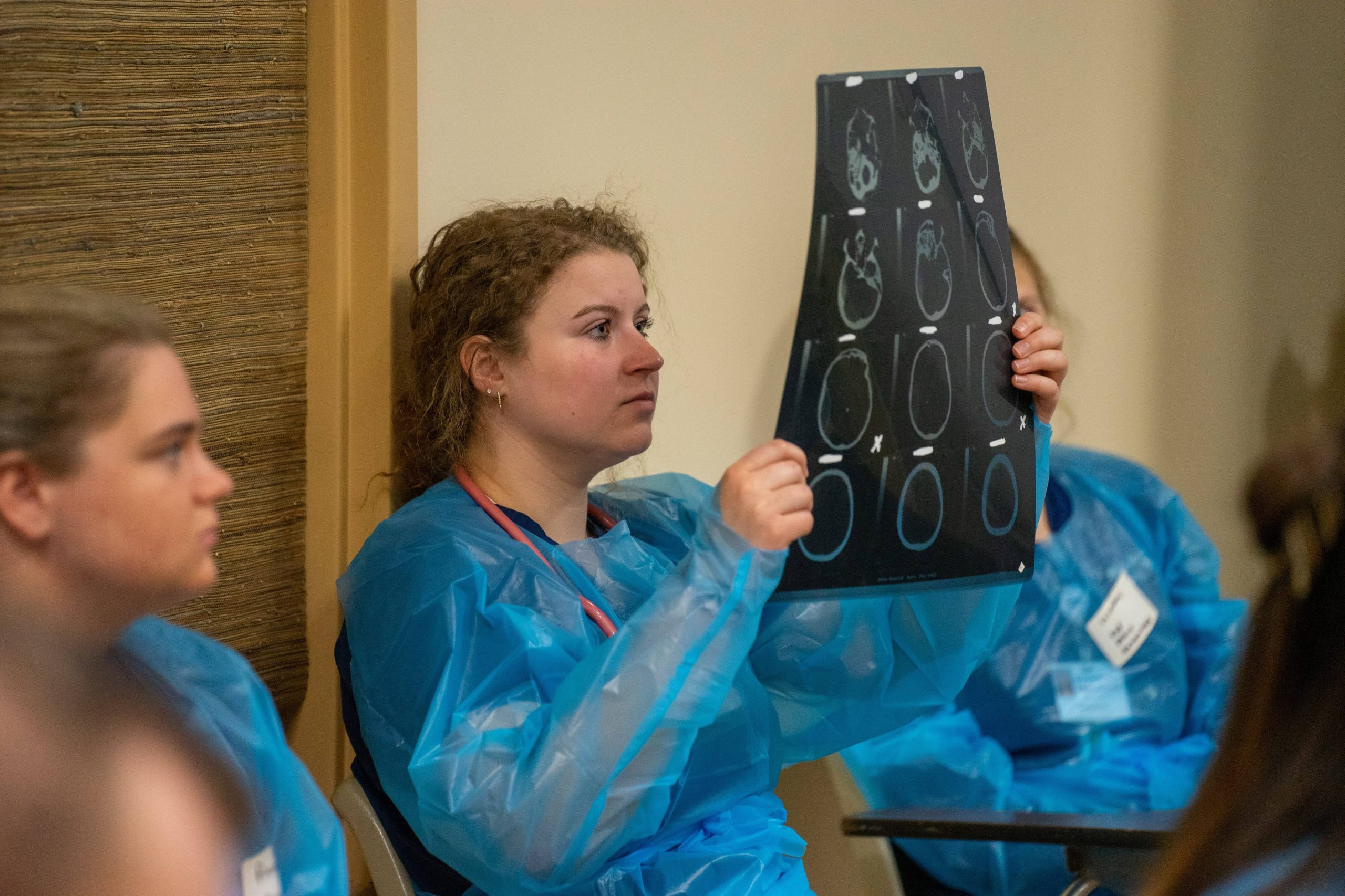 nursing students dressed in scrubs examining an x-ray
