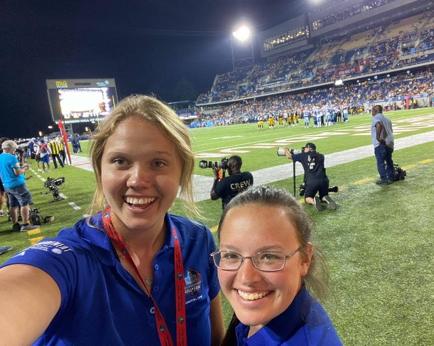 two women taking a selfie on the sidelines of a football field