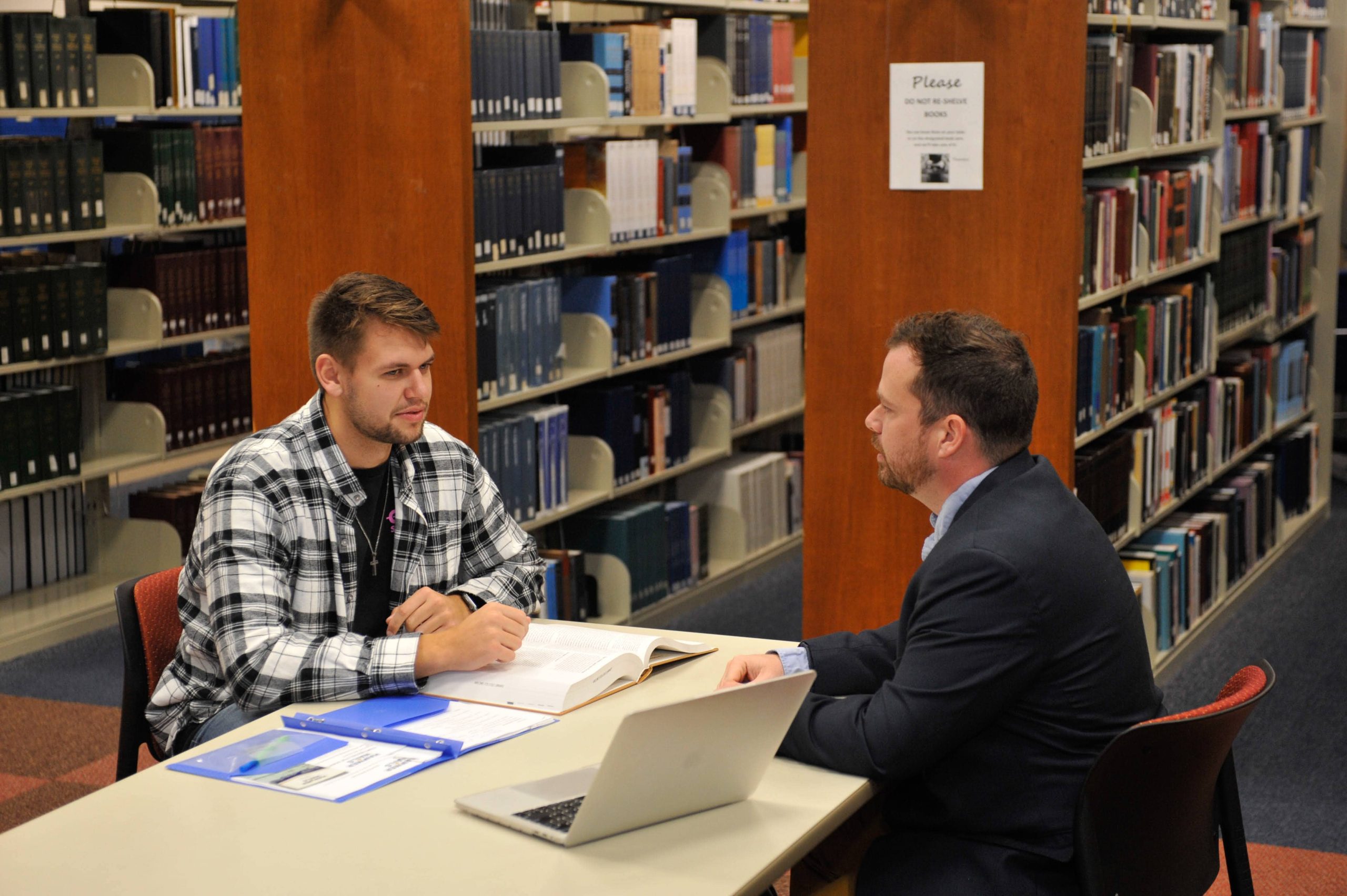 two guys sitting at table in the library