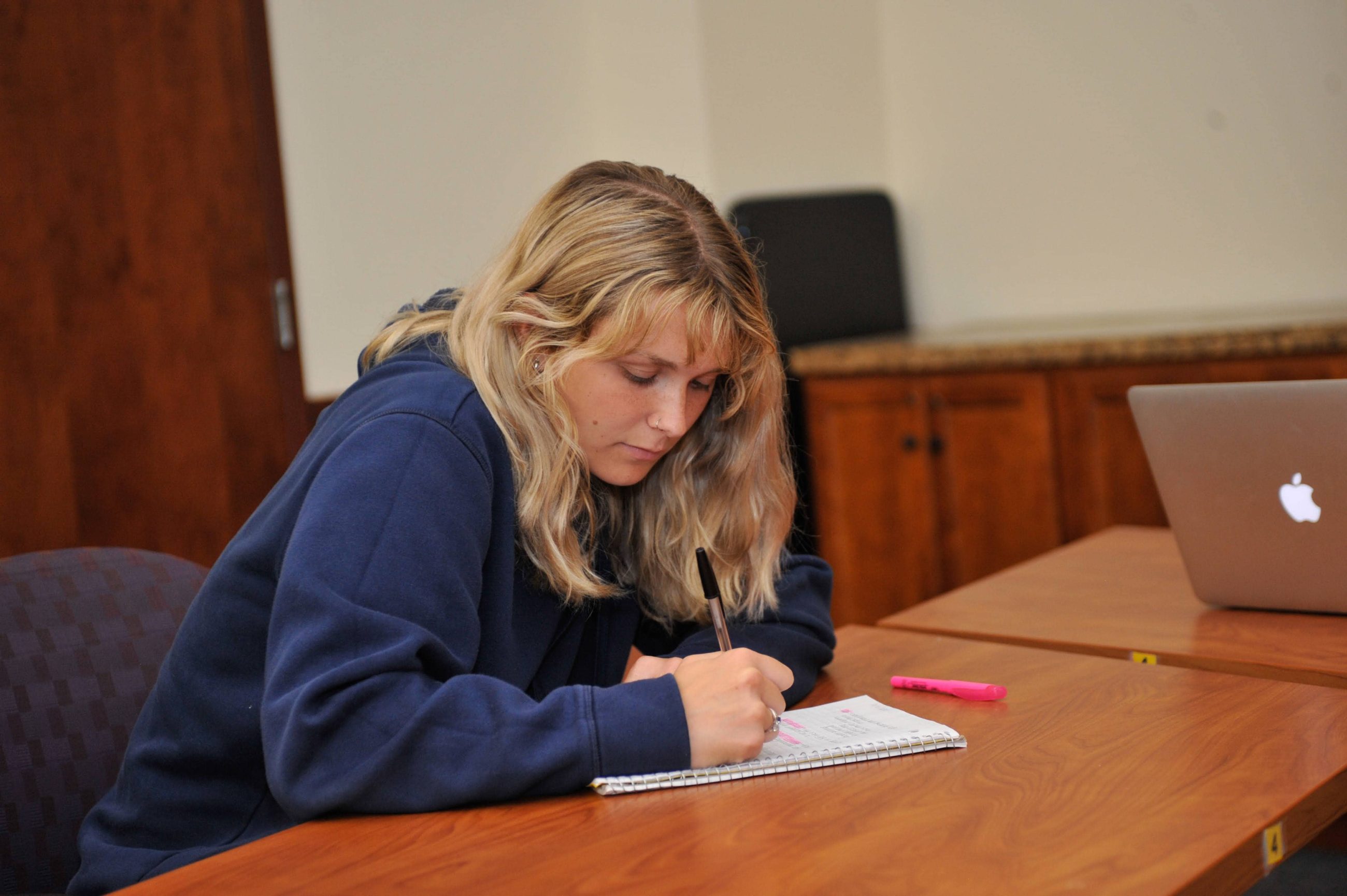 blonde female writing at desk
