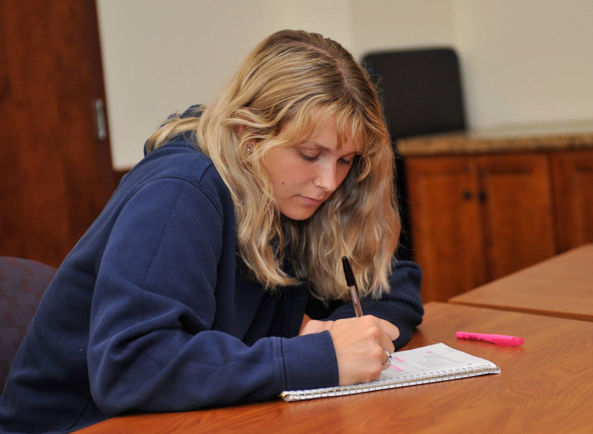 blonde female writing at desk