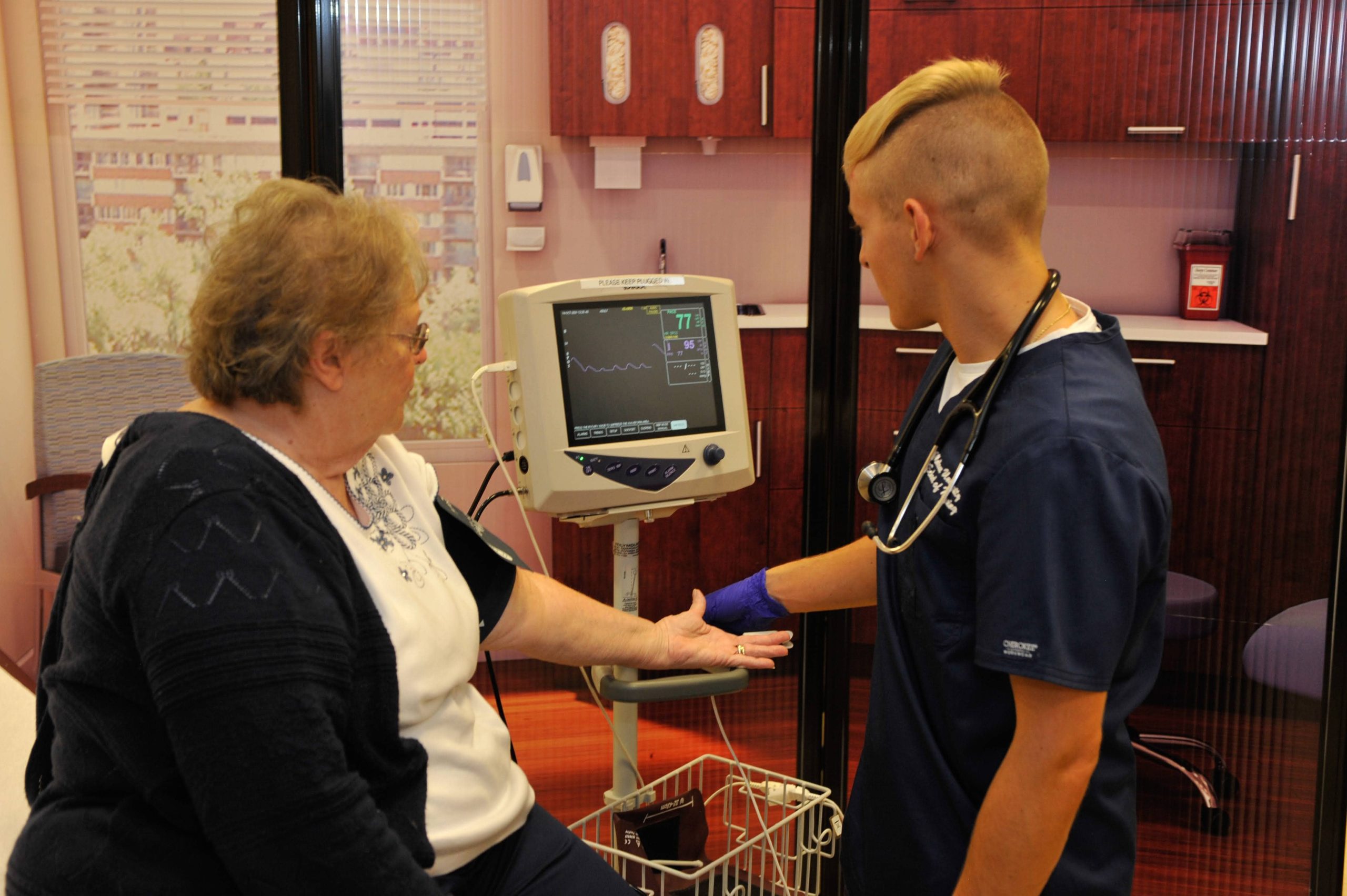 male nursing student attending female patient - both viewing monitor screen