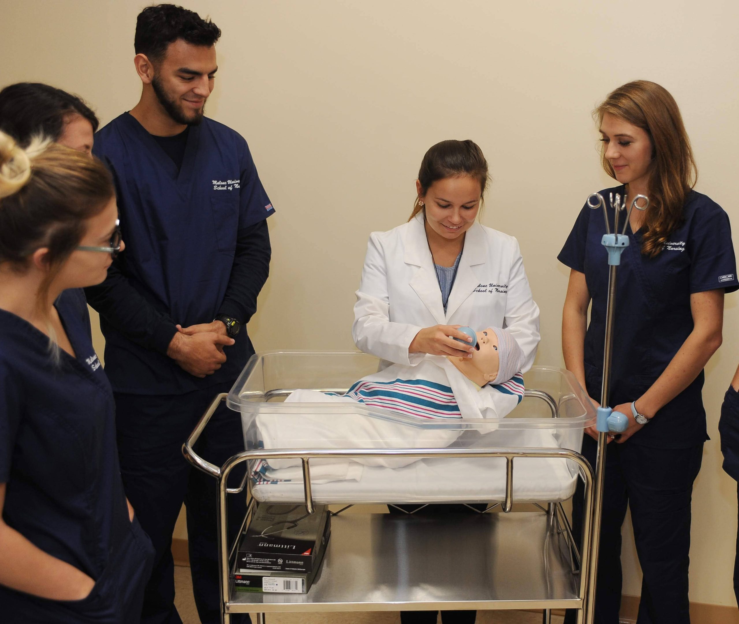 Several nursing students and instructor gathered around baby incubator