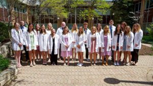 2023 Nursing grads in white coats in JC courtyard