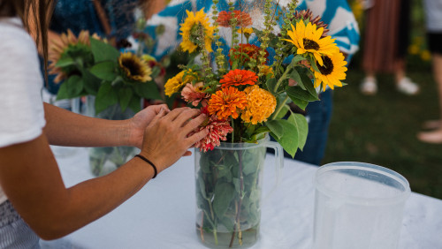 bouquet of flowers on table with hands arranging them