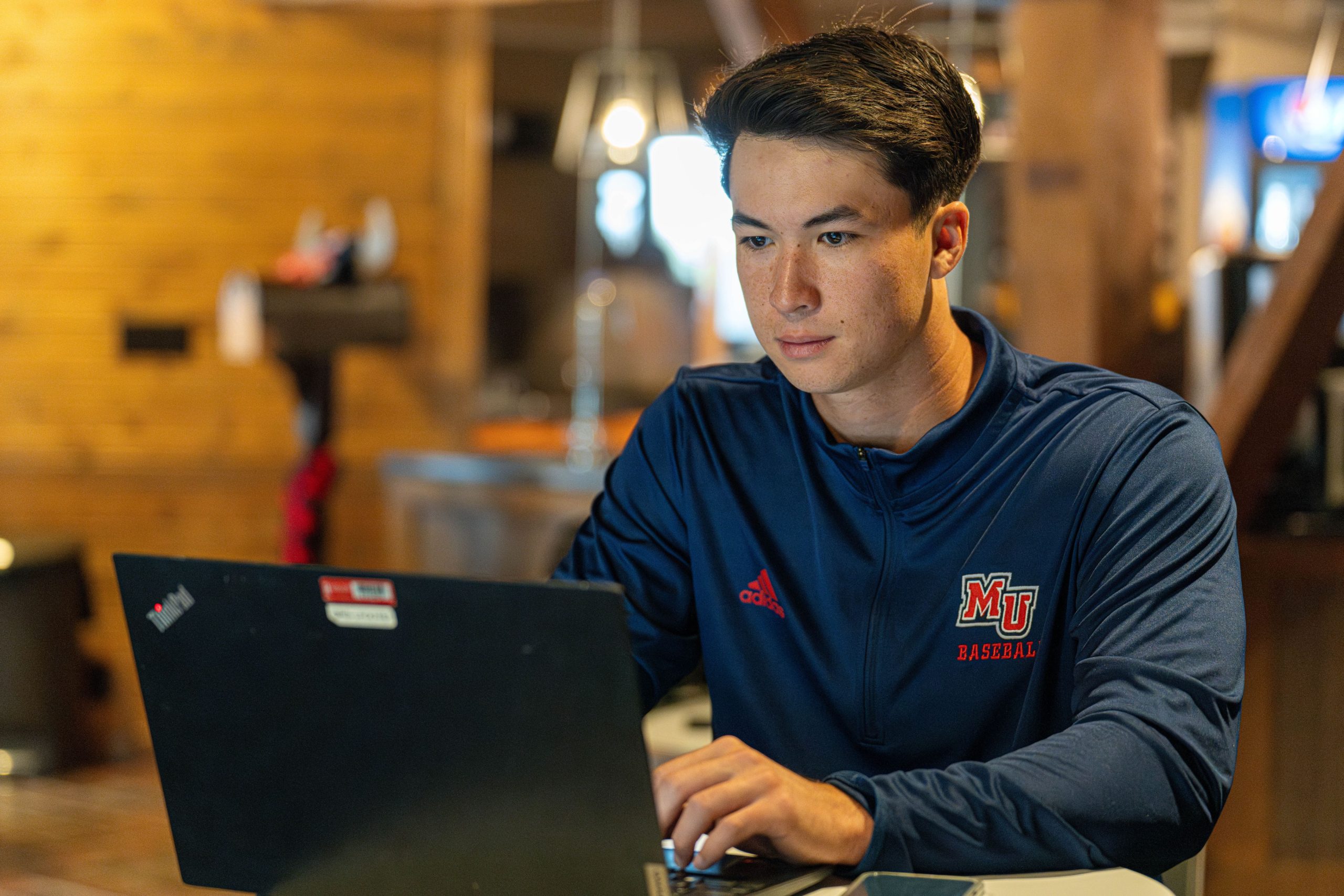 male student wearing a blue shirt working on his lap top