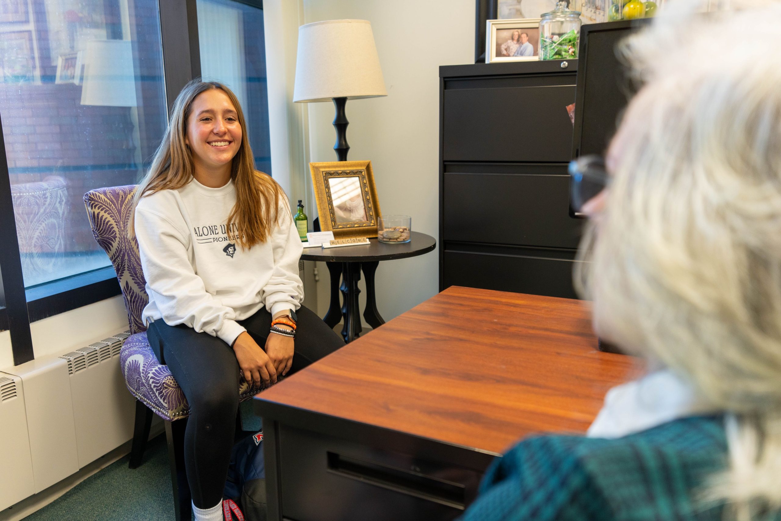 student sitting in a chair across from professor