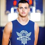 Male student smiles at camera wearing a blue basketball jersey