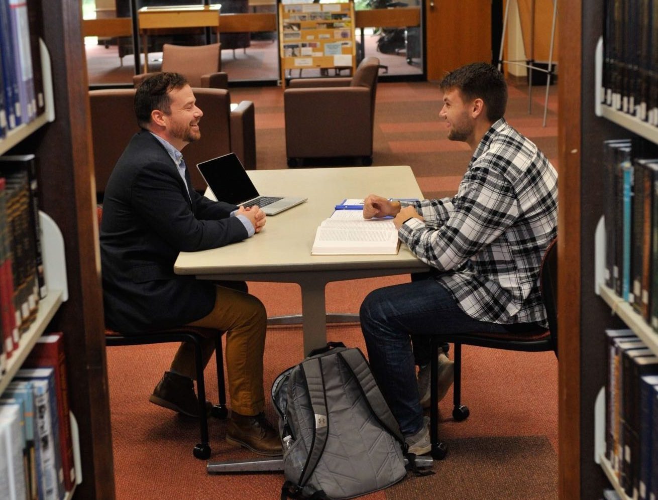 two male students sitting at a table in the library