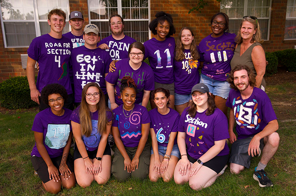 Small group of diverse Malone students smile wearing matching purple shirts