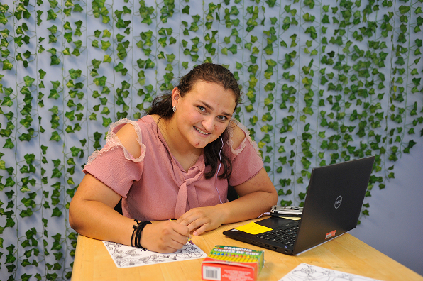 Female Malone student smiles as she studies at a laptop