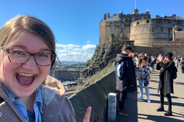 Female Malone student stands on a bridge outside a castle on a study abroad trip