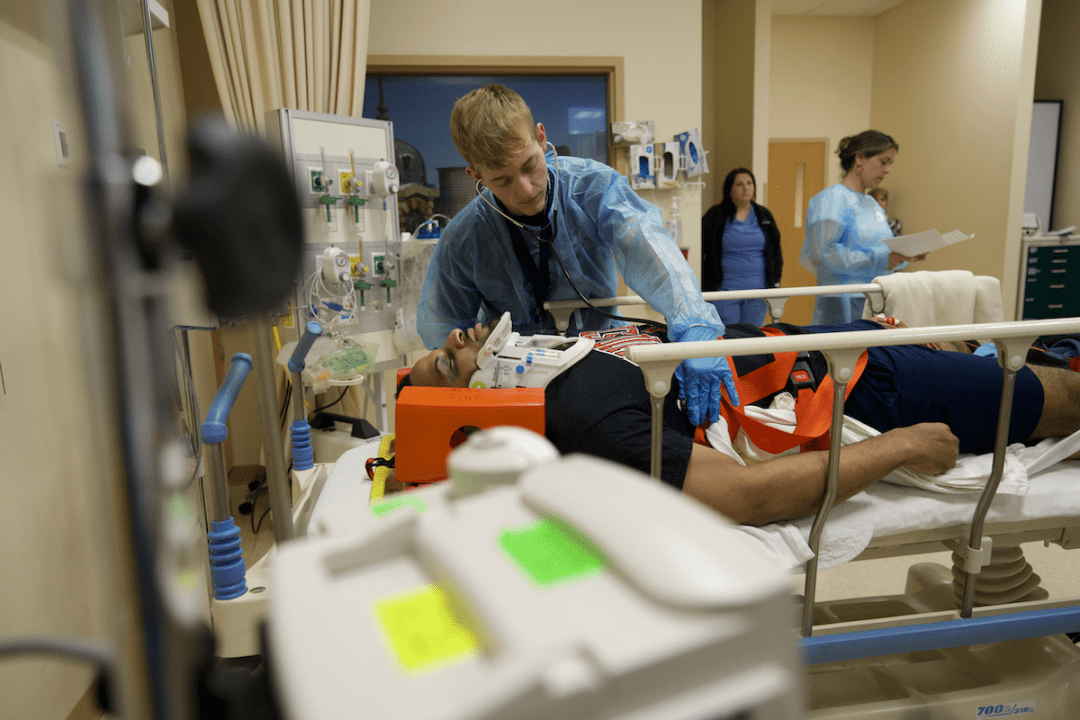 A male student works on a nursing mannikin in a simulation lab setting