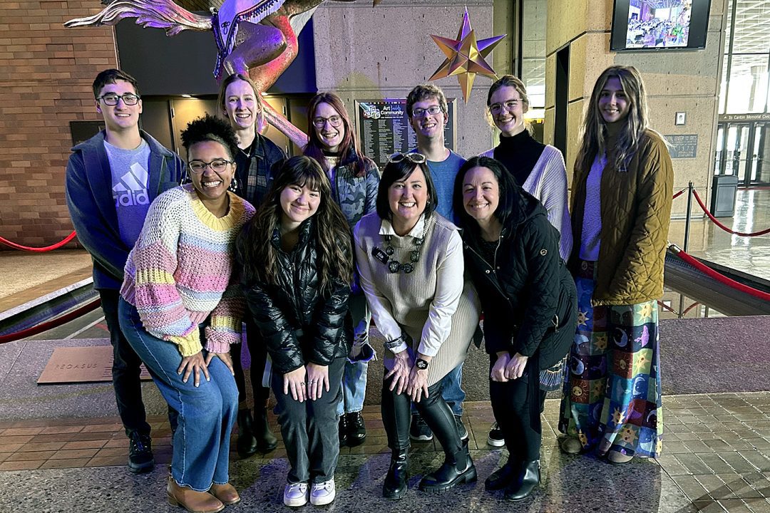 Ryan Karp posing with her students inside Canton Cultural Center lobby