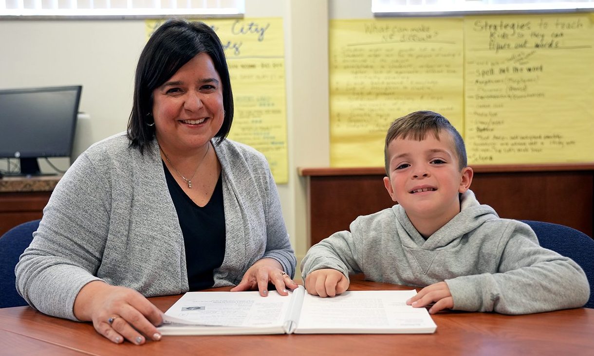 smiling female teacher seated next to male child student