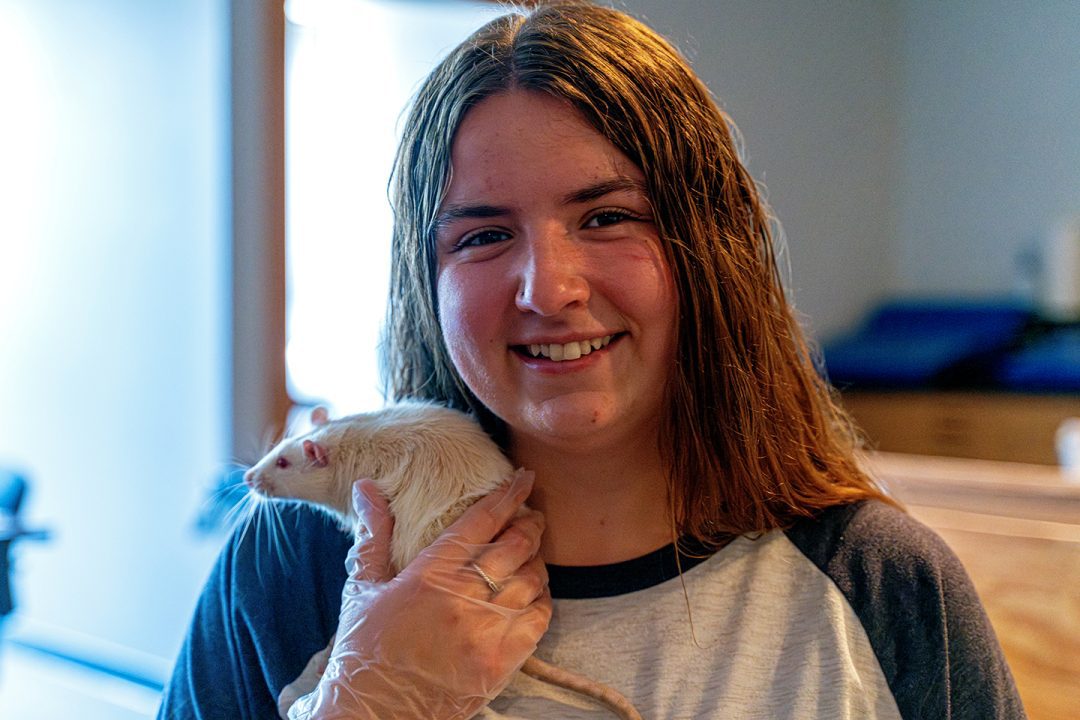smiling female psychology student holding white rat