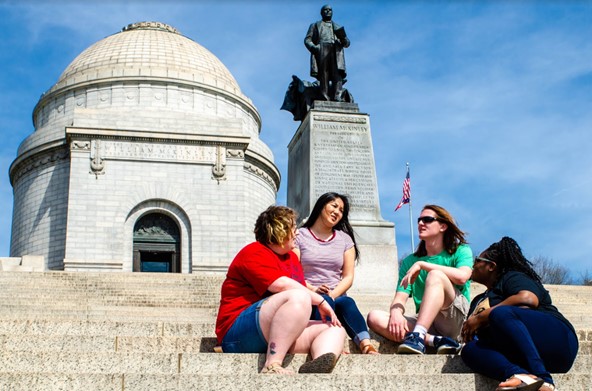 Four students sit on the steps outside the dome of the McKinley Monument on Canton, Ohio